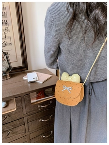 Dettaglio della mini borsa arancione per bambini con fiocco giallo e motivi a cuori neri