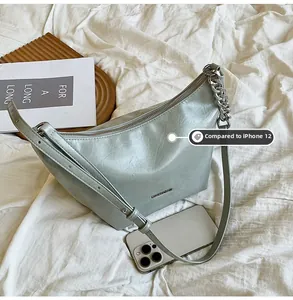 Size comparison of light green leather shoulder bag with iPhone 12 showing interior capacity