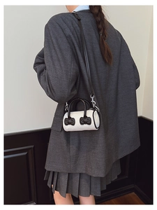 Detail of a mini beige corduroy bucket bag with black leather handles and cute bows