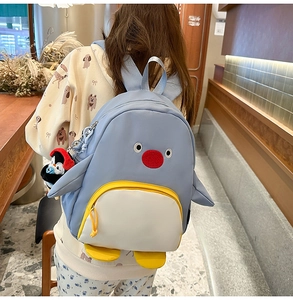 Détail d'un sac à dos pingouin bleu mignon avec broderie et pendentif en peluche