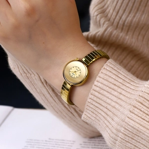 Elegant gold quartz watch with elastic metal strap on a knitted sweater sleeve