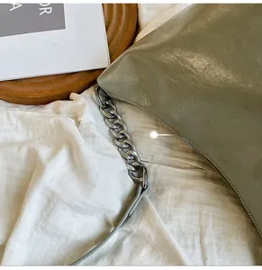 Detailed shot of glossy leather shoulder bag featuring robust silver metal chain links