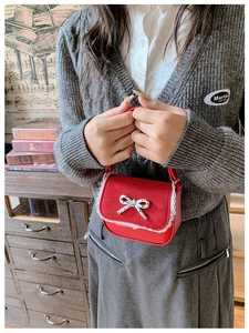 Détail du mini sac vintage rouge avec bordure en dentelle blanche et nœud en métal argent