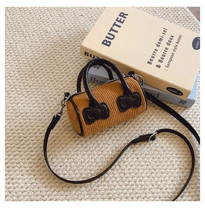 Detail of yellow corduroy mini bucket bag with dark brown synthetic leather bow accents