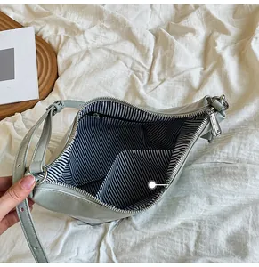 Sage green leather bag interior view with black and white striped lining and zip pocket