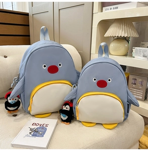Détail du sac à dos pingouin bleu clair avec grand sac et pendentif en peluche assorti