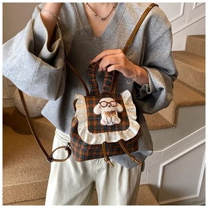 Detail of checkered toddler backpack with lace trim and plush puppy on model's back