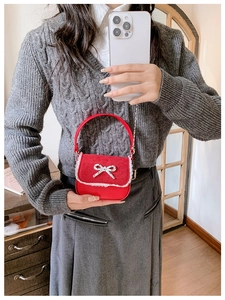 Détail du mini sac rouge enfant avec nœud, dentelle et chaîne argentée