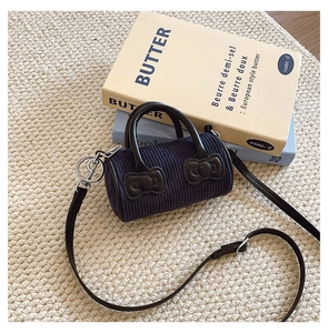 Close-up of navy blue corduroy bucket bag for kids featuring decorative leather bows