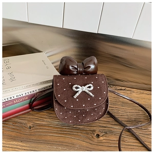 Dettaglio mini borsa a tracolla marrone con pois a cuore e grande fiocco su legno