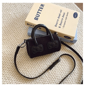 Detail of black corduroy bucket bag with PU bow accents and detachable shoulder strap