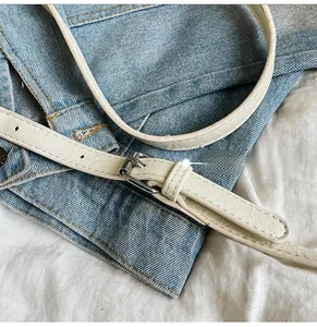 Close-up of white lychee leather strap and silver metal buckle on a shoulder bag