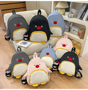 Détail de sacs à dos pingouin mignons en noir, gris, bleu et rose avec des porte-clés