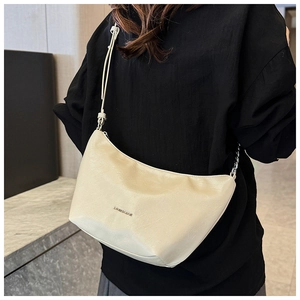 Detail of cream crescent shoulder bag featuring metal logo and refined leather texture
