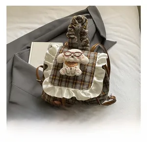 Detail of kids plaid backpack featuring lace trim and a 3D plush puppy decoration