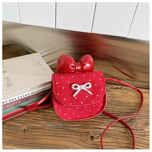 Dettaglio borsa bimba in camoscio rosso con motivi a cuore e grande fiocco decorativo