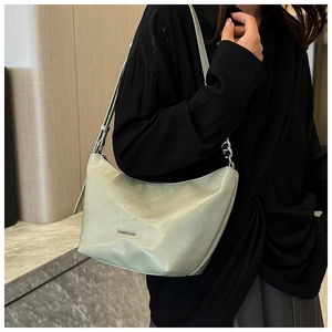 Detail of sage green shoulder bag featuring leather texture and silver chain strap