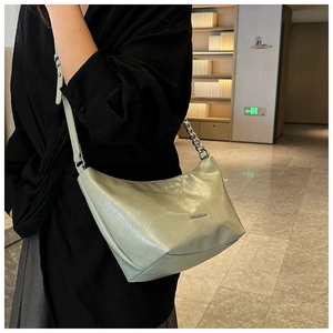 Detail of light green leather underarm bag with silver chain strap and smooth finish