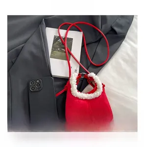 Detail of red suede mini handbag with white faux fur handle and smartphone for scale