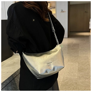Detail of silver metallic hobo bag with crushed texture and chain strap on a model
