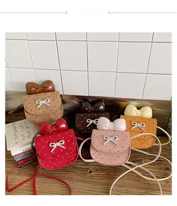 Dettaglio delle mini borse a tracolla per bambini con fiocco in cinque colori su legno
