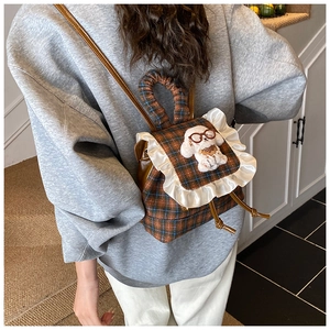 Close-up of kids plaid backpack featuring lace trim and a cute poodle doll accessory