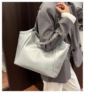 Close-up of metallic silver tote bag with pleated texture and silver chain strap