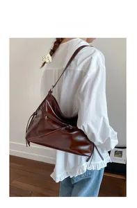 Detail of a dark brown glossy PU leather hobo bag with a decorative knotted shoulder strap