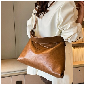 Brown leather tote bag shown on shoulder with vintage texture and large capacity