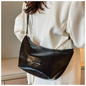 Close-up of a glossy black moon-shaped shoulder bag with silver logo and chain strap detail