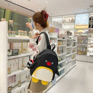 Sac à dos mignon pingouin pour femme avec pendentif, présenté dans un décor de magasin
