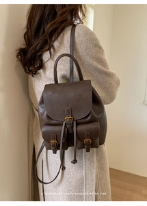 Detail of vintage brown leather backpack with brass buckles shown on a model