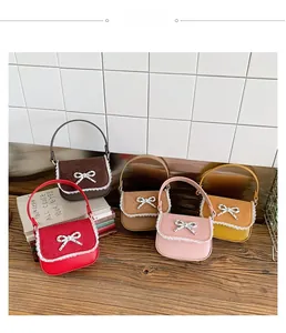 Détail de cinq mini sacs enfant avec bordure dentelle et nœuds argentés sur bureau