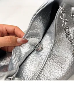 Detail view of the silver metallic tote bag showing the magnetic buckle closure system