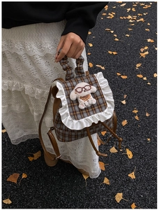 Detail of grid pattern kids backpack with lace trim and plush dog doll on top