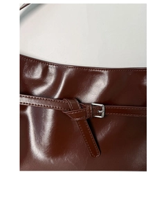 Detail of glossy brown PU leather shoulder bag with buckle and fine stitching