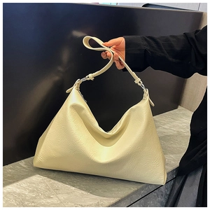 Detailed view of the soft pleated leather texture and metal rings on a cream tote bag