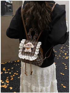 Outdoor shot of a plaid backpack featuring lace ruffles and a plush puppy doll on a child