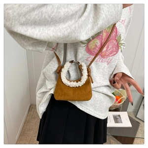 Gros plan d'un mini sac à main en daim marron avec poignée en fausse fourrure blanche