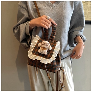 Detail of checkered mini backpack with lace trim and plush puppy doll for kids