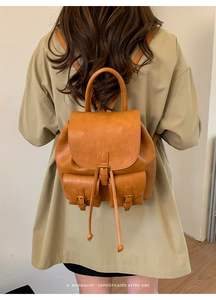 Rückansicht eines braunen Lederrucksacks im Retro-Stil mit zwei Vordertaschen und Schnallen