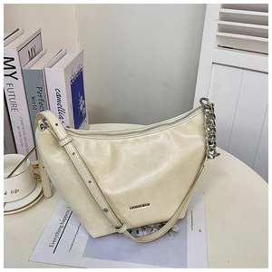 Detailed close-up of cream hobo bag with silver chain strap and LOUIE&MART logo on a table