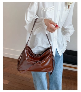 Close-up of deep brown glossy leather tote bag with stylish side knot detail