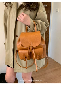 Detail of retro brown faux leather backpack with drawstring and dual front pockets