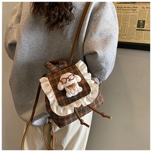 Detail of checkered toddler backpack with lace trim and plush puppy character