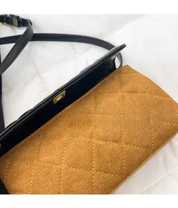 Close-up of diamond-quilted brown suede handbag with golden twist lock and black strap