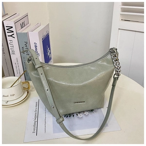 Detail view of mint green crescent bag with silver chain and glossy faux leather texture