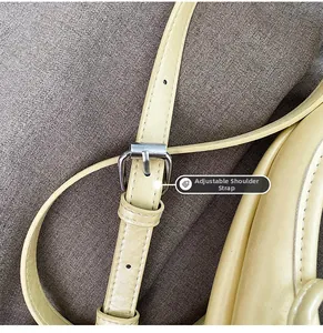 Detail of adjustable strap with silver buckle on light yellow vegan leather handbag