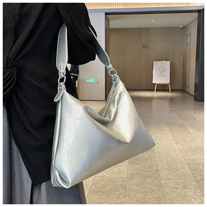 Detailed view of silver metallic hobo bag with pleated texture and wide shoulder strap