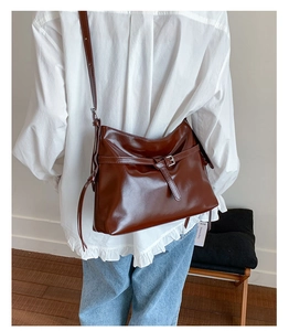 Detail shot of a dark brown PU leather tote bag with adjustable strap on a model